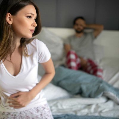 Sad, upset, unhappy woman holding hands on stomach suffering from stomach pain